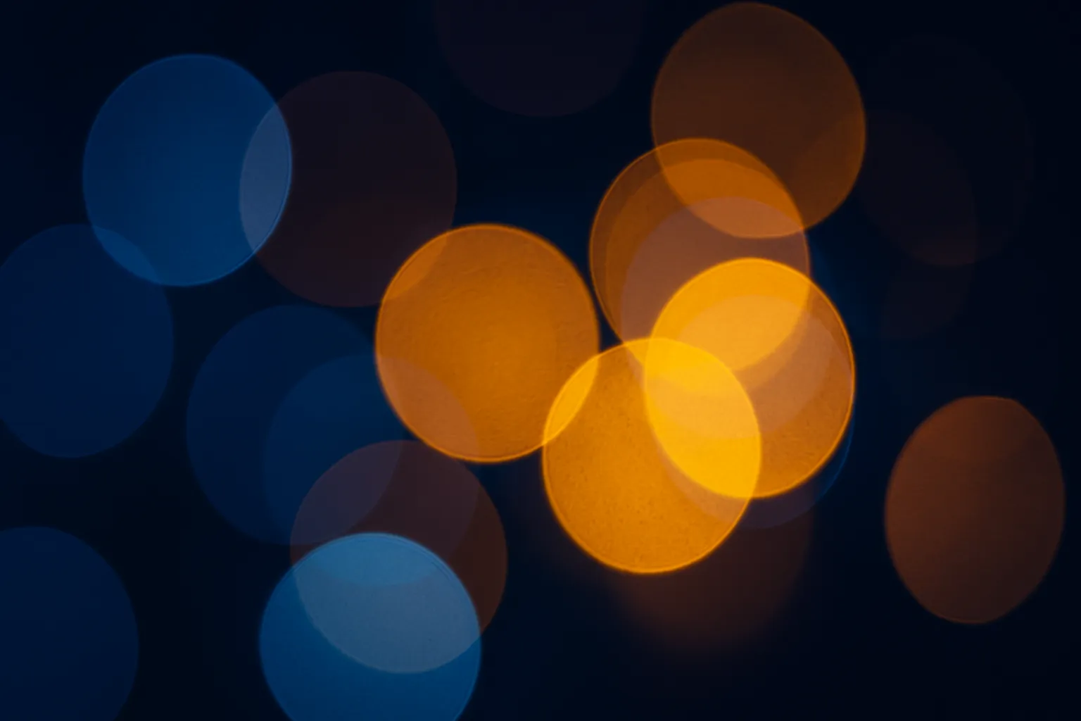 Soft abstract bokeh lights in warm orange and cool blue tones, blurred night background