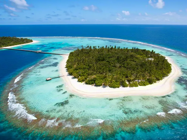 Beautiful round island with white sandy beach and blue ocean lagoon.