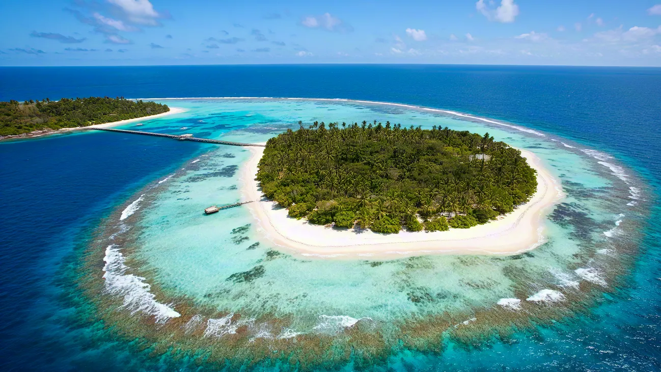 Beautiful round island with white sandy beach and blue ocean lagoon.