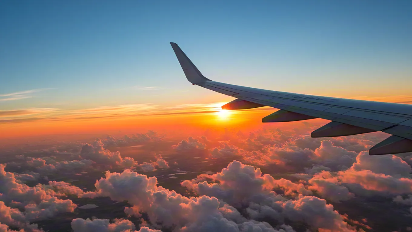 View from plane window at sunset over clouds