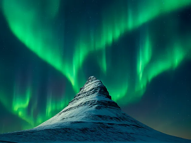 orthern lights above a snowy mountain peak