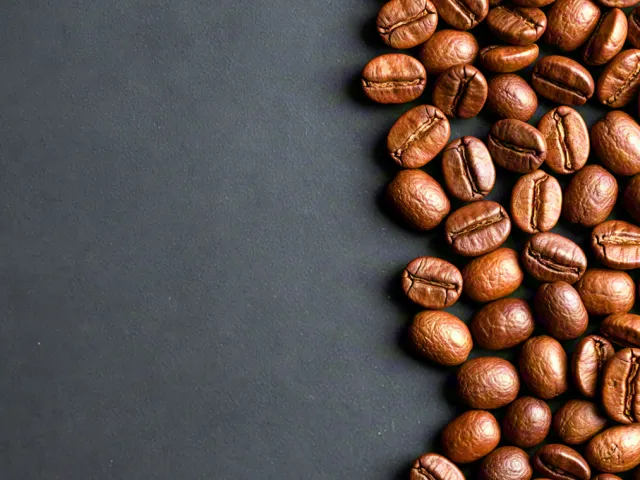 Roasted coffee beans scattered on black surface
