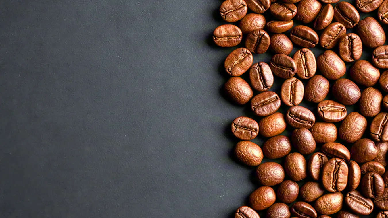 Roasted coffee beans scattered on black surface