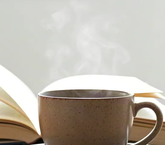 Warm daylight on cups of coffee beside open book.