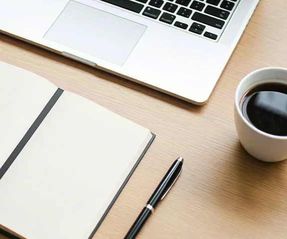 Top view of workspace with notepad, pen, and warm coffee mug.