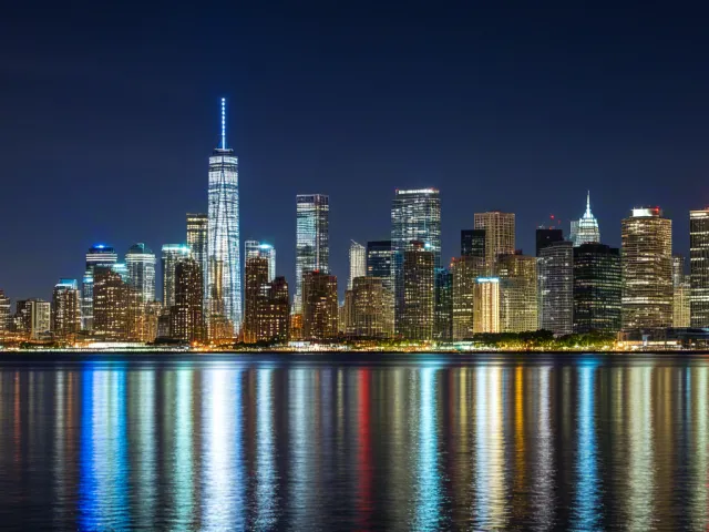 Beautiful night skyline with colorful reflections on still water.