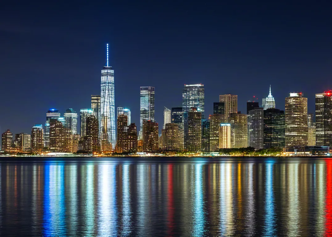 Beautiful night skyline with colorful reflections on still water.