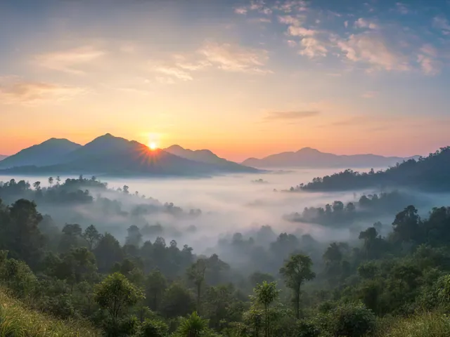 Peaceful sunrise over mountain range and forest valley filled with soft morning mist.