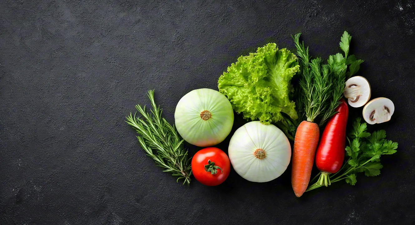 Assorted vegetables including tomatoes, carrots, and lettuce on black surface.