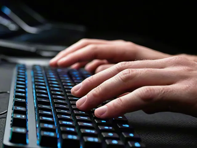 Close-up of hands typing on illuminated computer keyboard