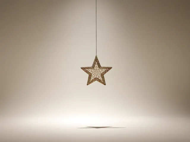 single gold star ornament hanging in soft warm light on minimal background
