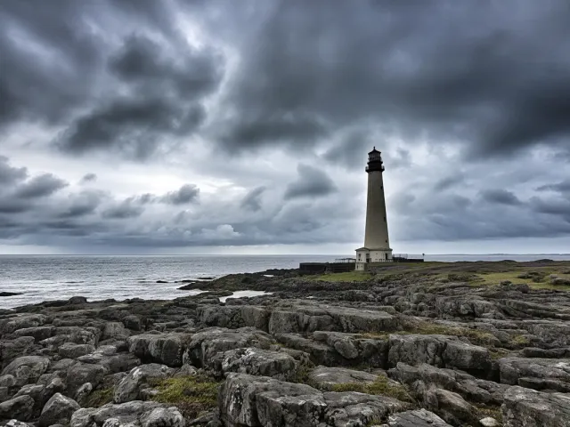 Storm clouds over lighthouse on rugged coast