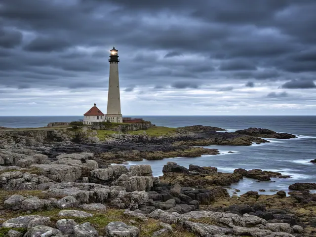Lighthouse surrounded by dramatic clouds and rocks
