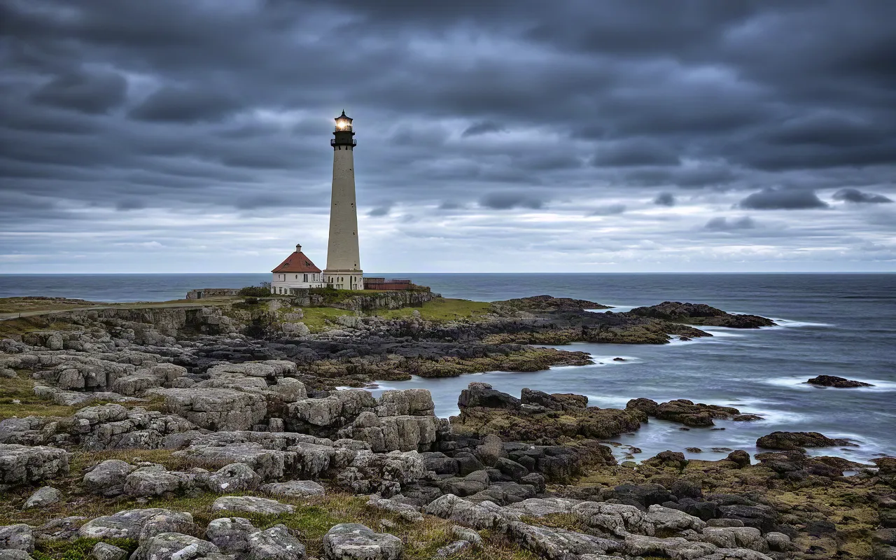 Lighthouse surrounded by dramatic clouds and rocks