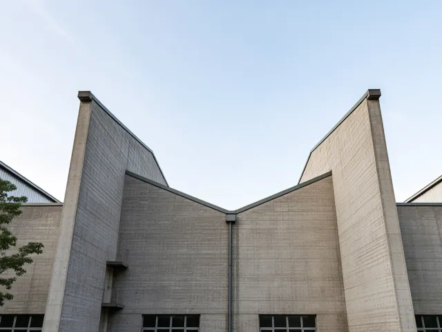 Architectural detail of gray concrete walls and sky in background.