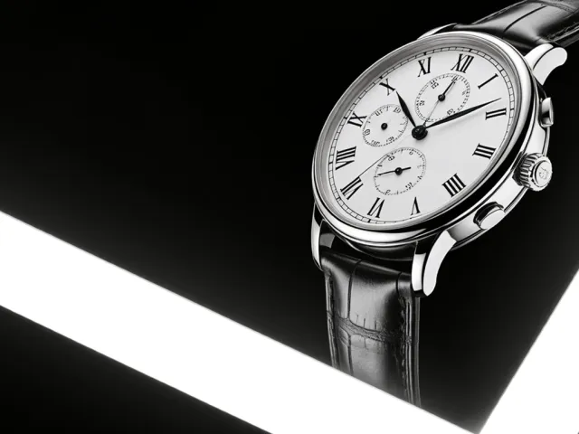 elegant wristwatch with metal strap on reflective black background