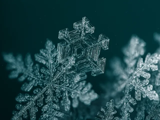 Close-up of detailed frozen snowflake with blue background.