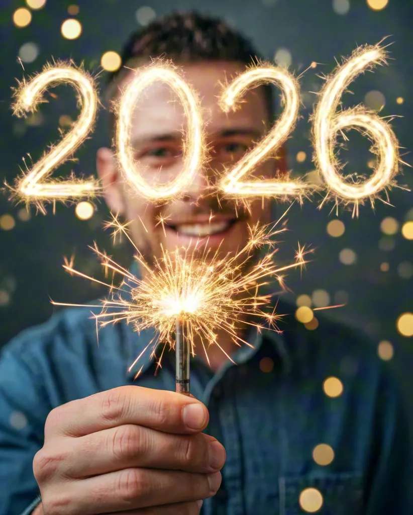 Man holding sparkler with glowing 2026 lights