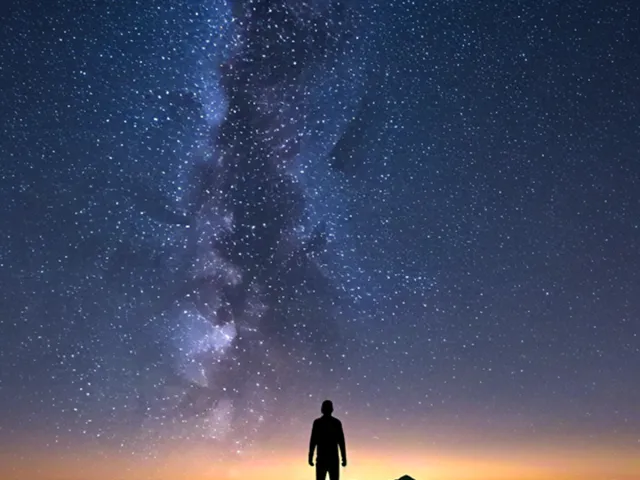 Silhouette of man beneath starry night sky