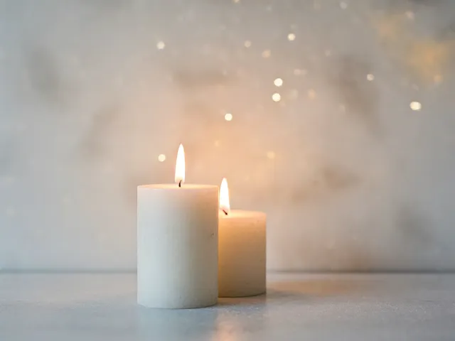 Two white candles surrounded by soft golden festive lights