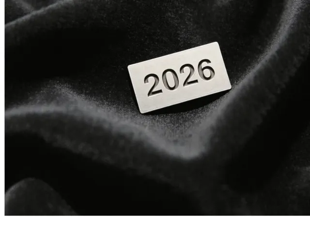 Black fabric background with a small white card labeled 2026