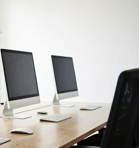Modern light-filled office with clean desks and computer monitors.