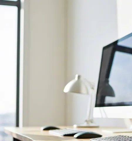 Row of sleek computers in minimalist office near white walls.