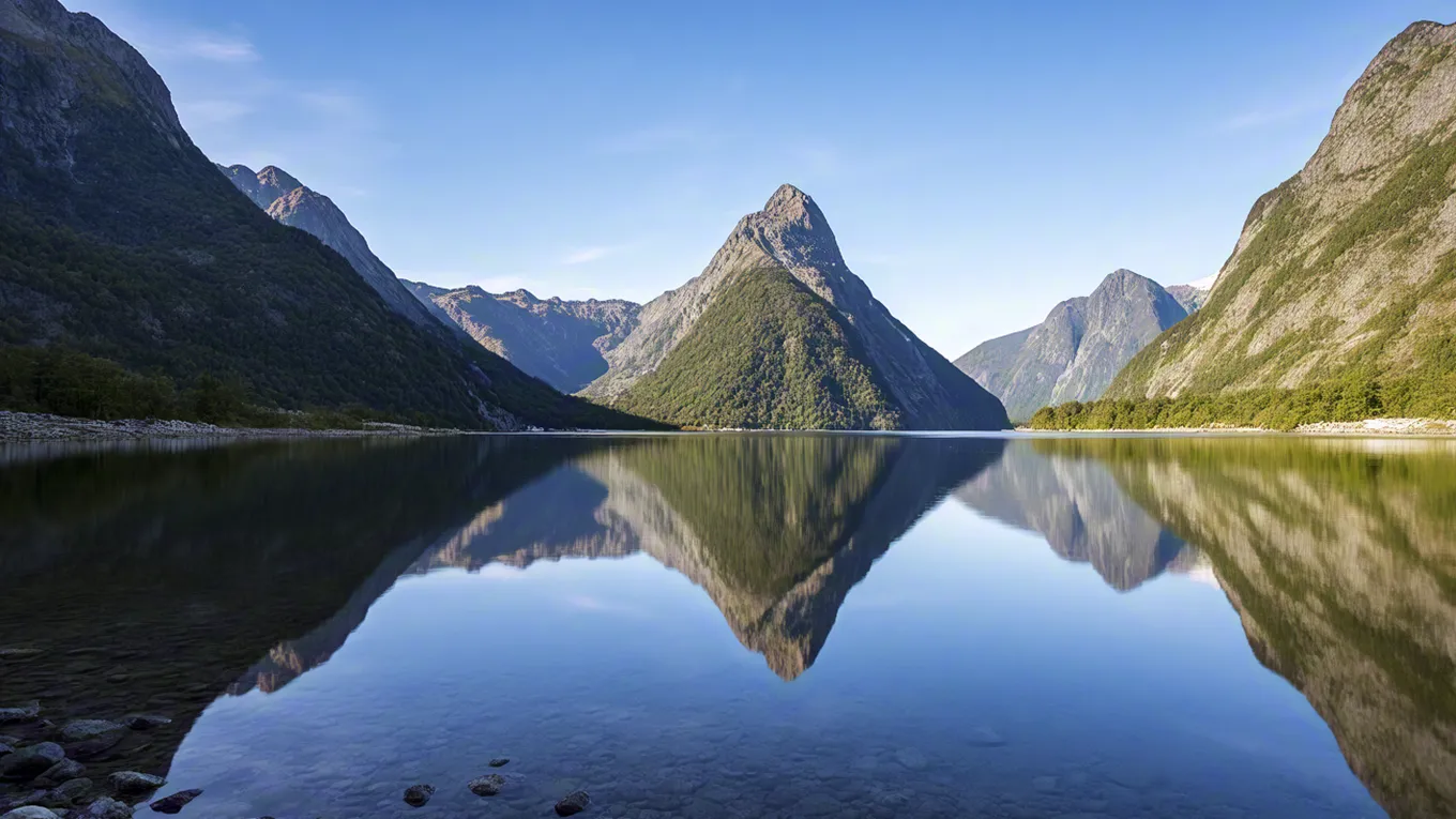 Clear mountain lake reflecting peaks and sky