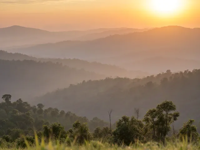 Peaceful mountain landscape at sunrise with soft mist and warm colors