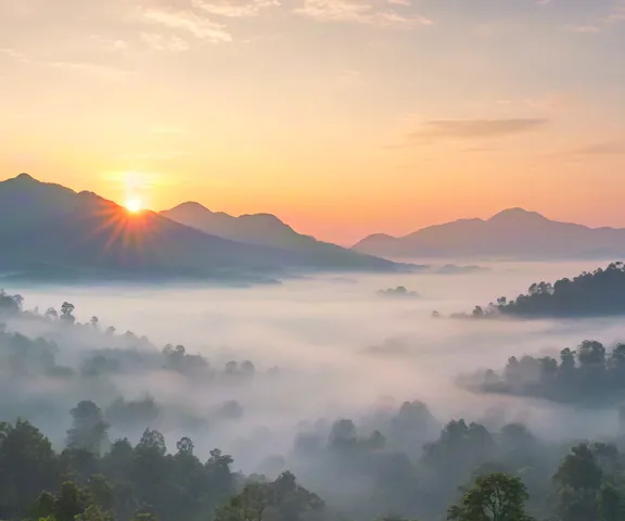 Gentle fog and light spreading across green mountain ridges.