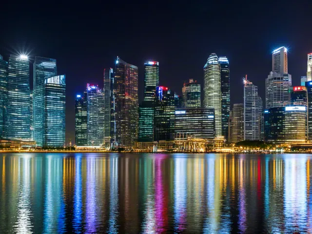 Skyline reflections on river showing vibrant lights and towers.