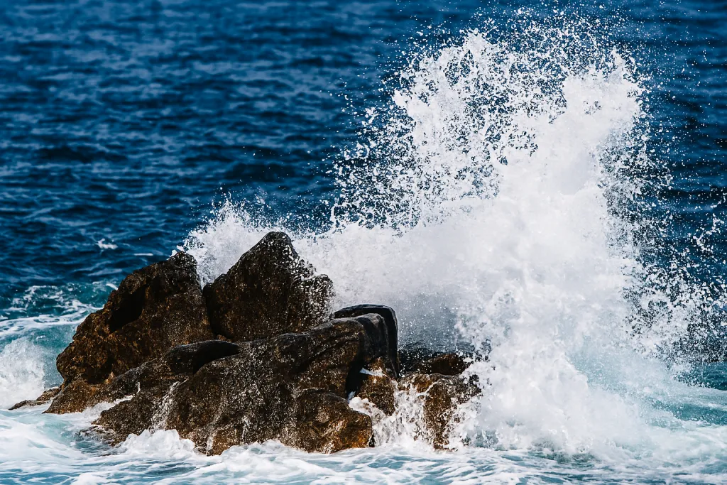 Powerful ocean wave crashing against coastal rocks