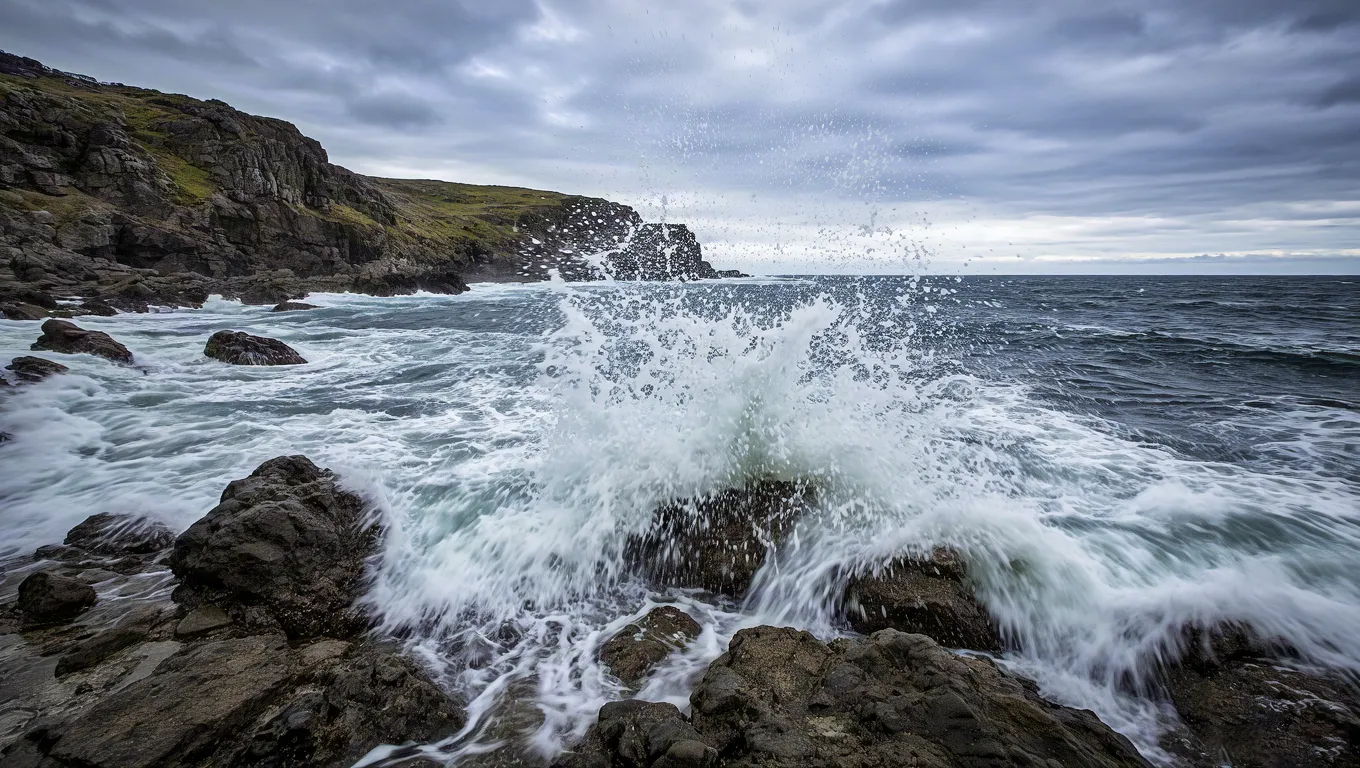 Ocean waves hitting rocks on cloudy day