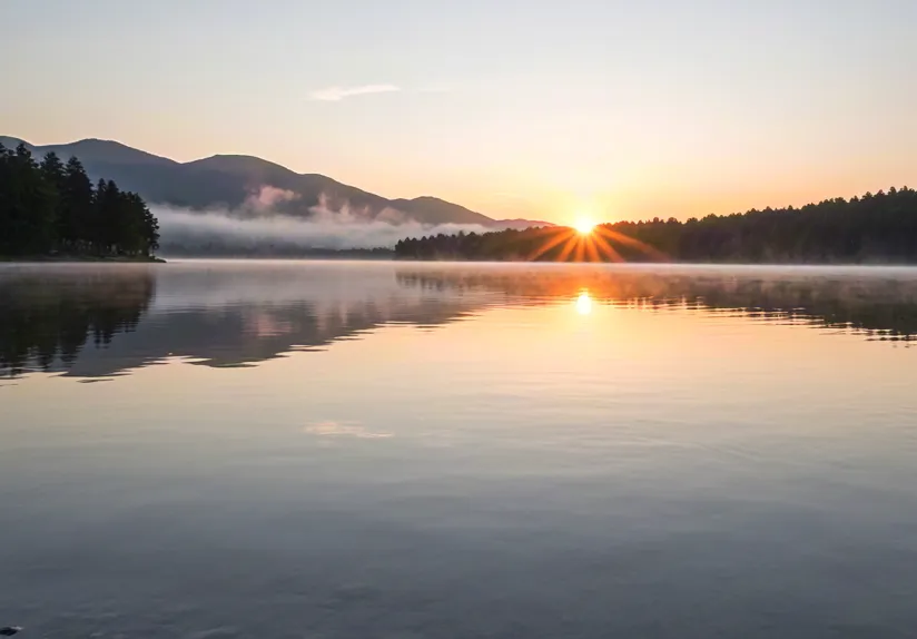 Sunrise over calm lake and mountains – peaceful nature reflection