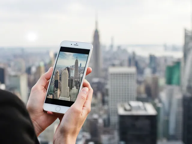 person photographing city skyline using a smartphone
