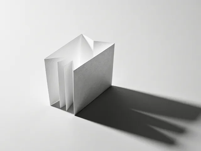minimal white geometric sculpture casting a shadow
