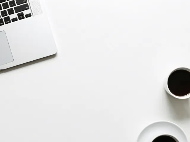 Minimalist top-down view of workspace with laptop and black coffee mug.