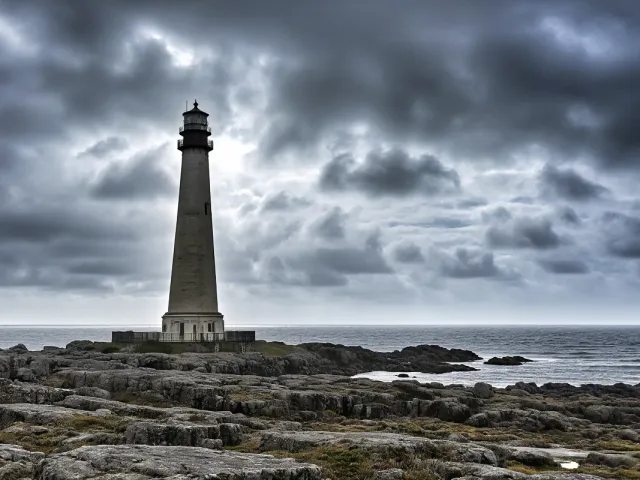 Lighthouse standing against stormy sea under dark dramatic clouds
