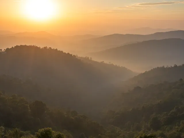 Atmospheric sunset casting golden light across foggy hills