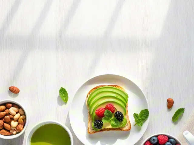 Flatlay of avocado toast, berries, and green tea on white table