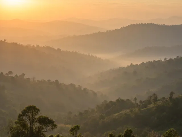 Soft orange sunrise illuminating misty layered hills