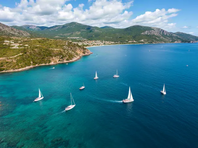 Aerial view of sailboats floating near a tropical beach and clear blue sea